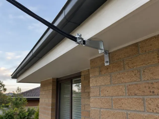 Overhead service cable with point-of-attachment bracket on a brick house exterior in Gateshead