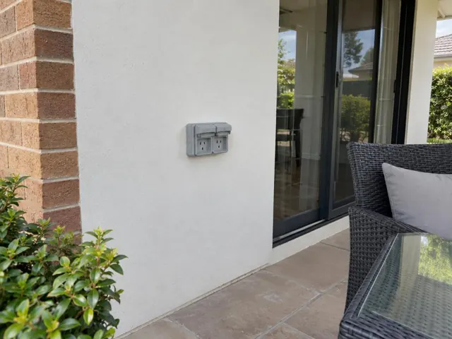 Outdoor double power point on a rendered exterior wall beside a patio door in Mount Hutton